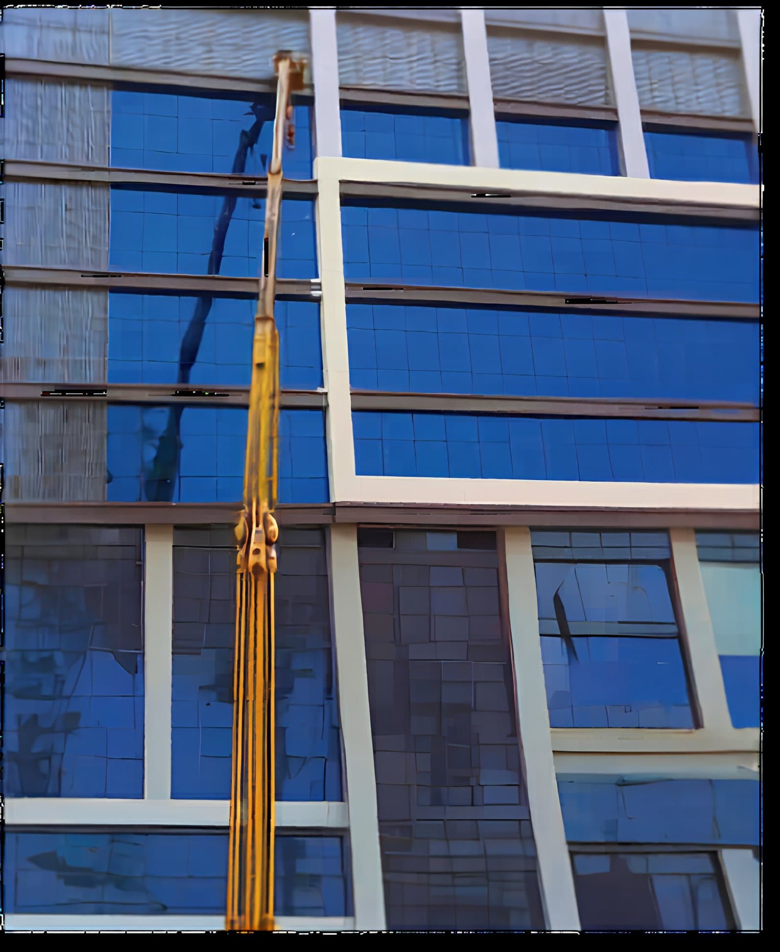 A crane hoisting cladding panels up the glass facade of Arkan Square Mall