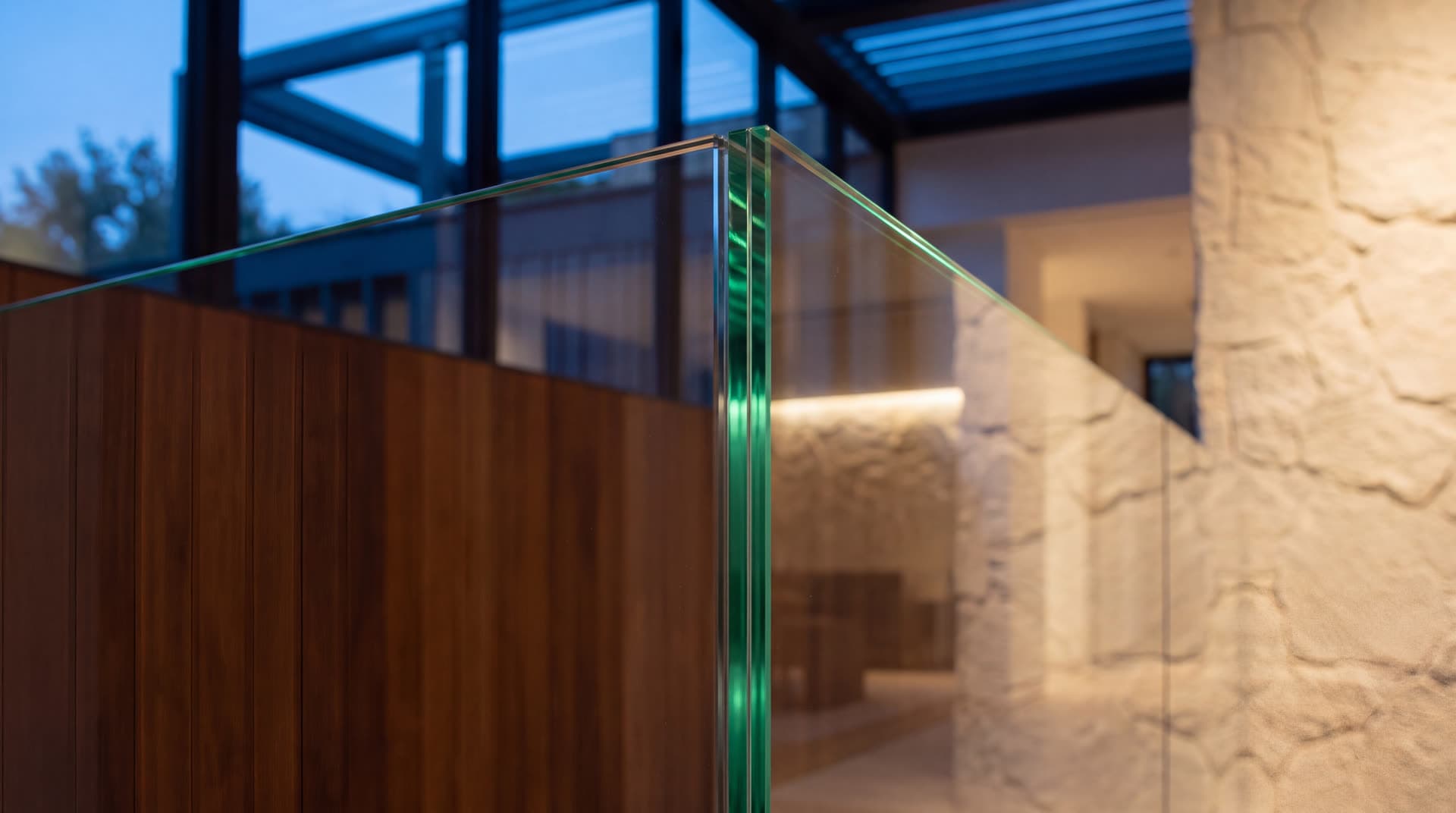 Edge of a glass partition beside timber and textured stone